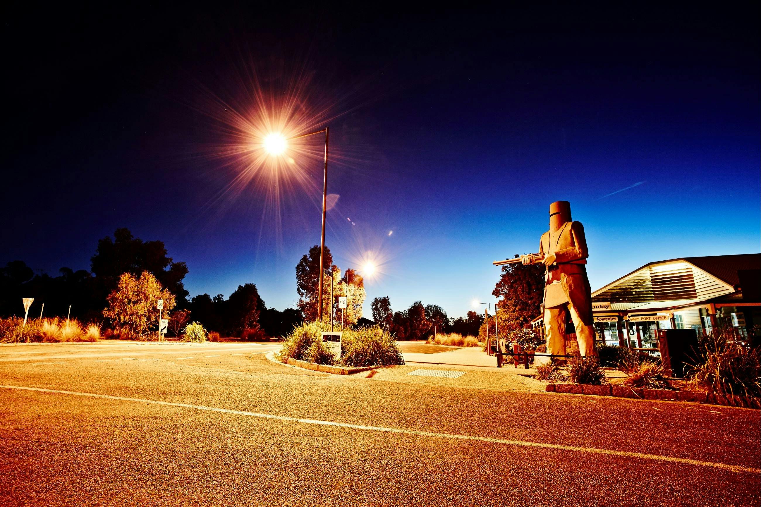 Across the road from statue lit up at night with shop in the background