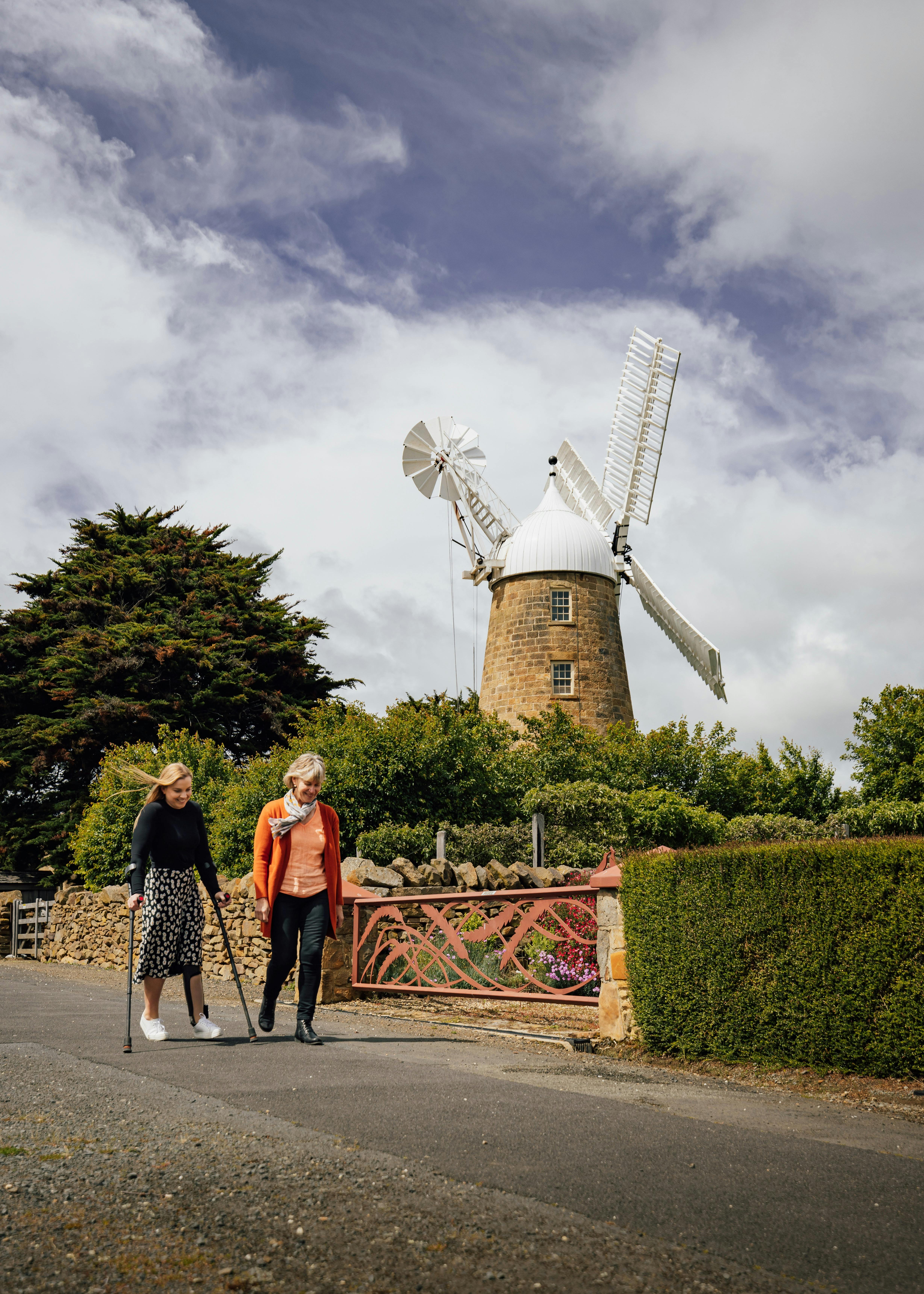 Two women walking with a windmill in the background