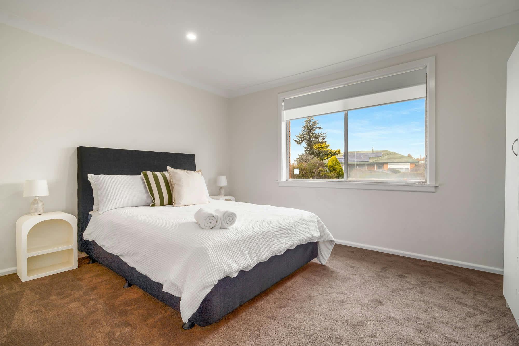 Queen bed with white side tables, and large window