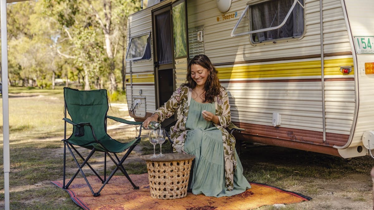 Camper relaxing with a glass of wine at Traveller's Rest 1770 Nature-campground in Agnes Water/1770
