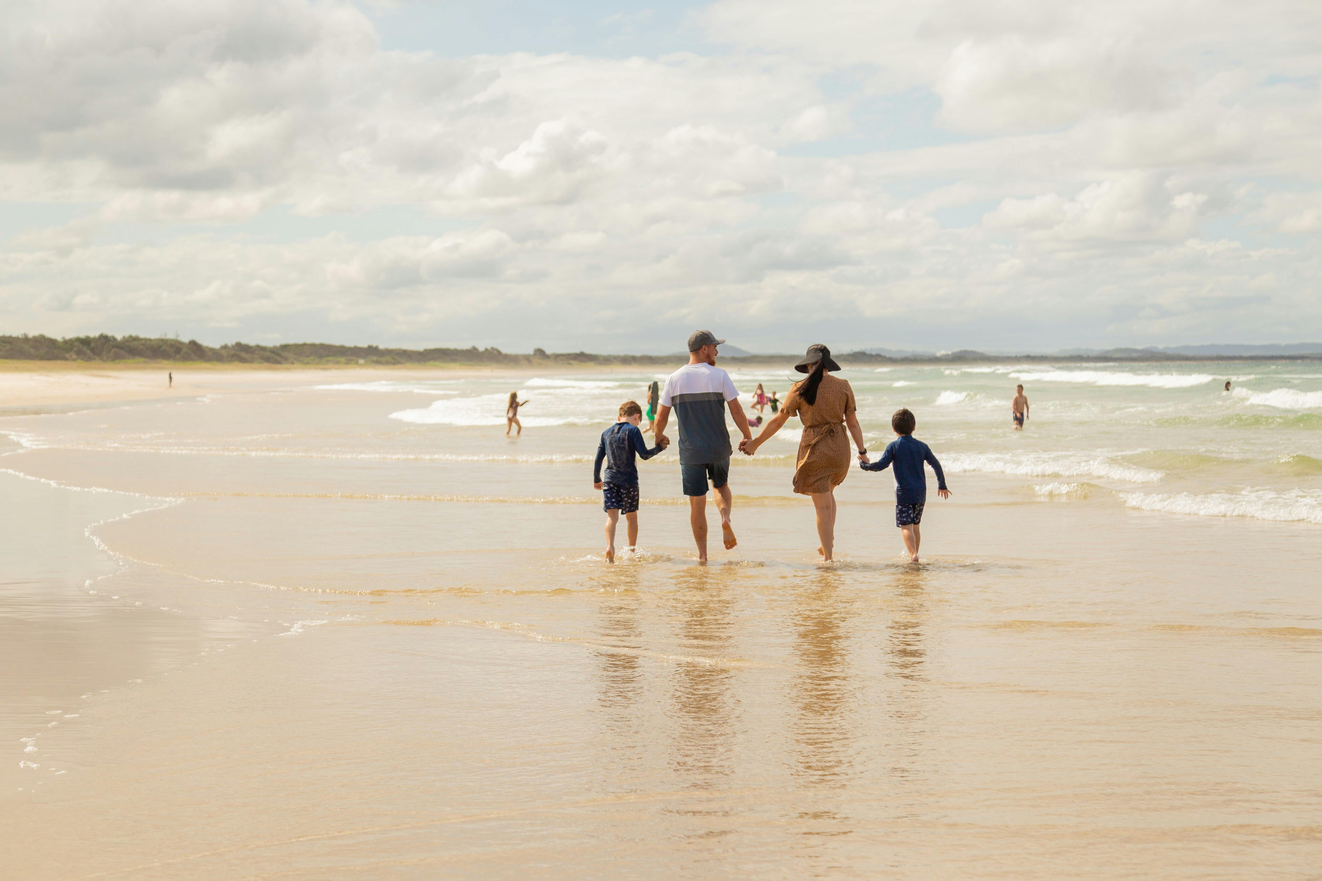 family walking along the edge of the water at the beach