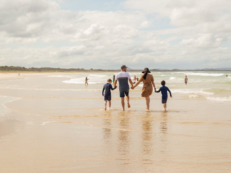 family walking along the edge of the water at the beach