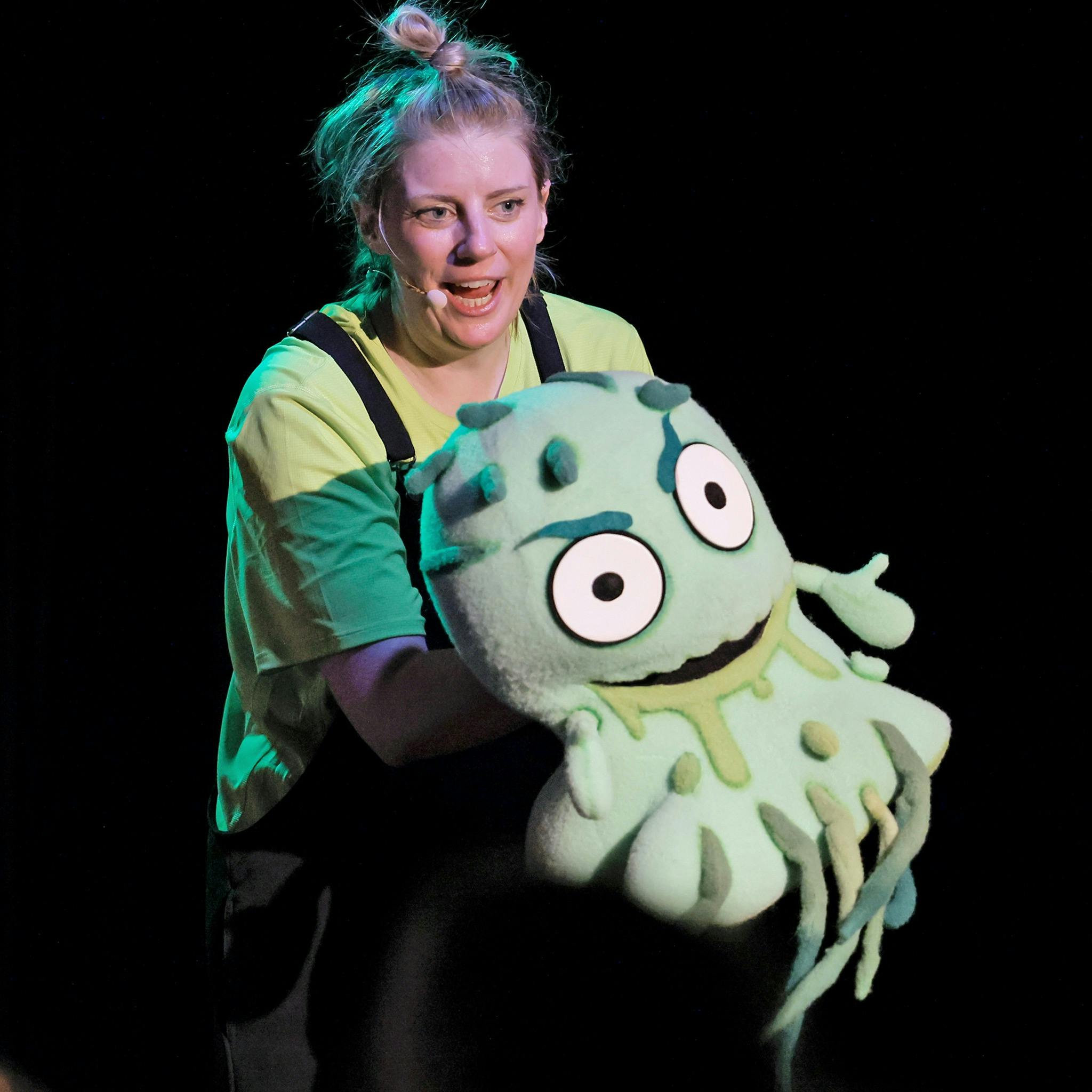 actor smiling holding a green snotty monster puppet