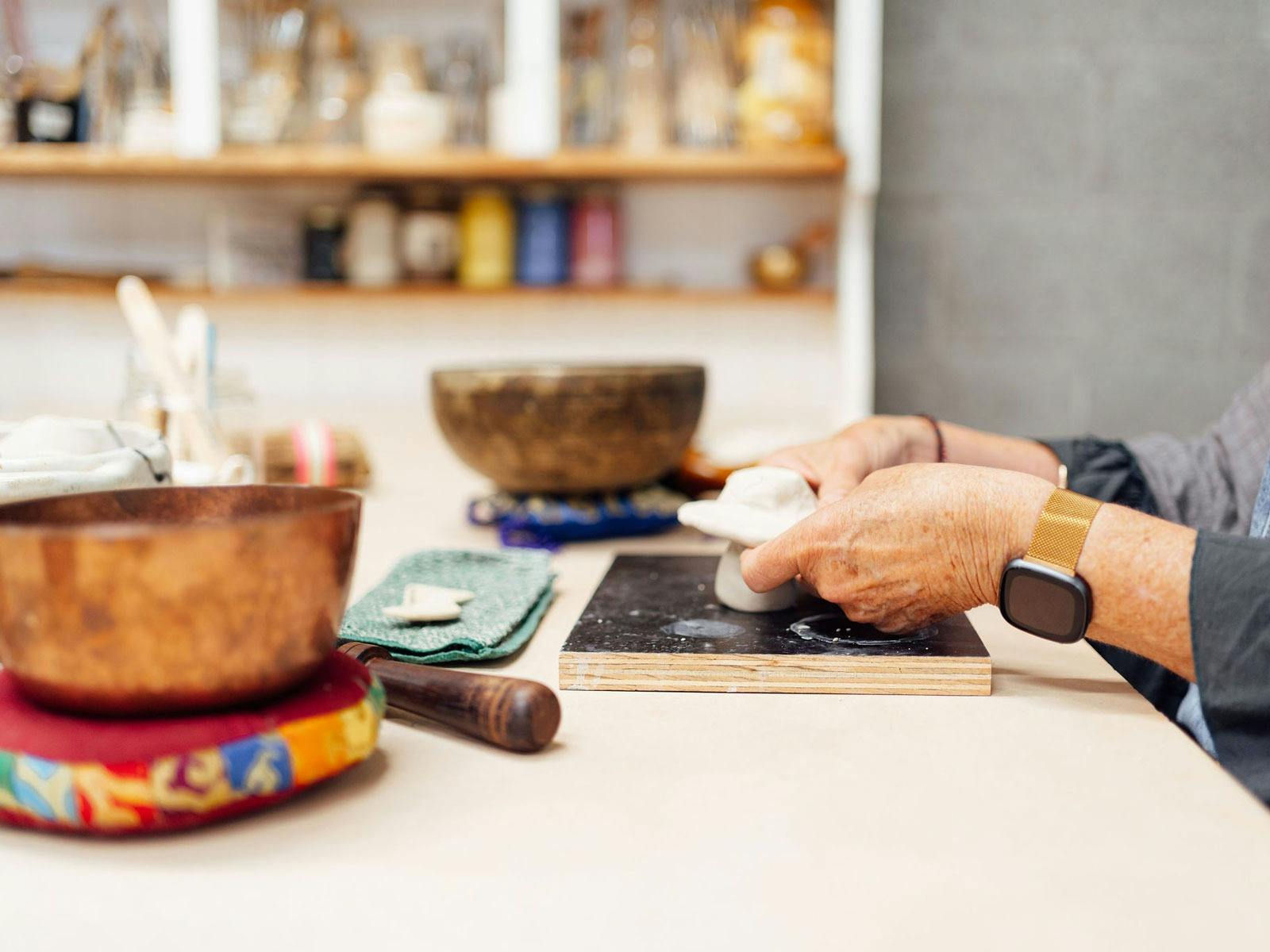 person playing with clay with meditation instruments placed around