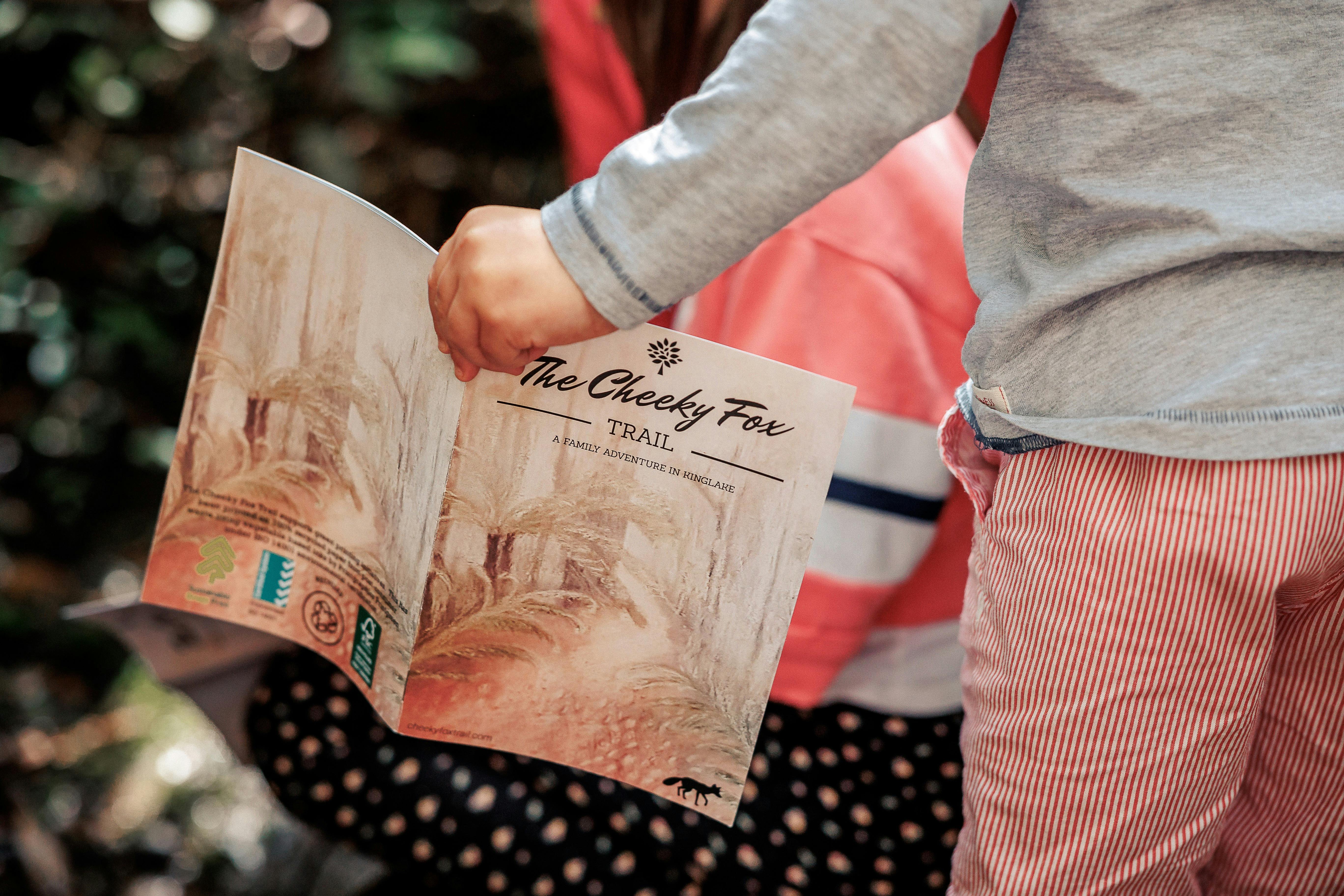 Child holding The Cheeky Fox Trail guide book