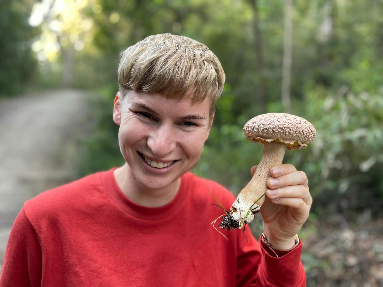 A girl holds up a shaggy bolete mushroom