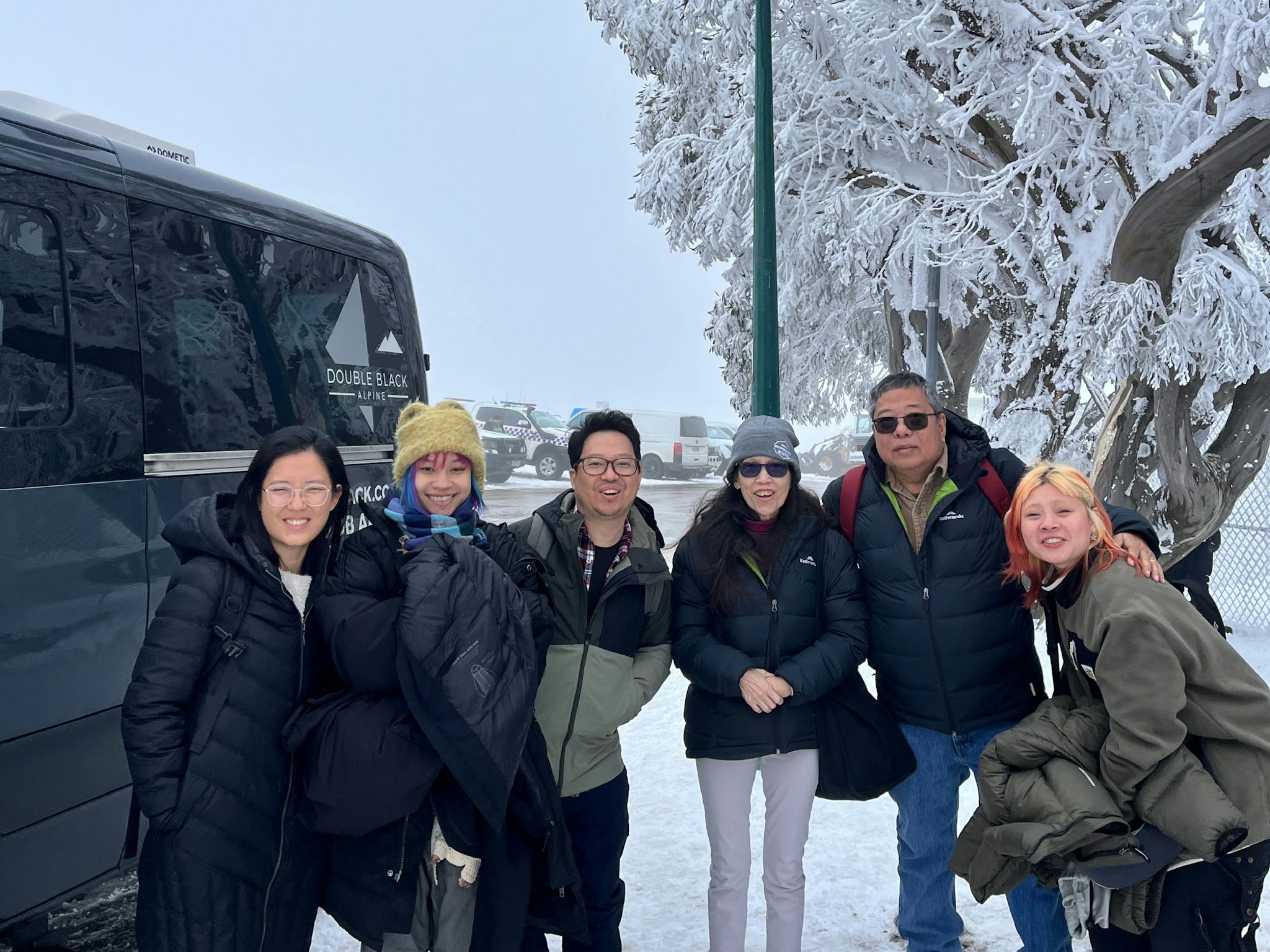 Guests of Double Black Alpine arrive at Mount Buller, standing near a snow-covered tree .