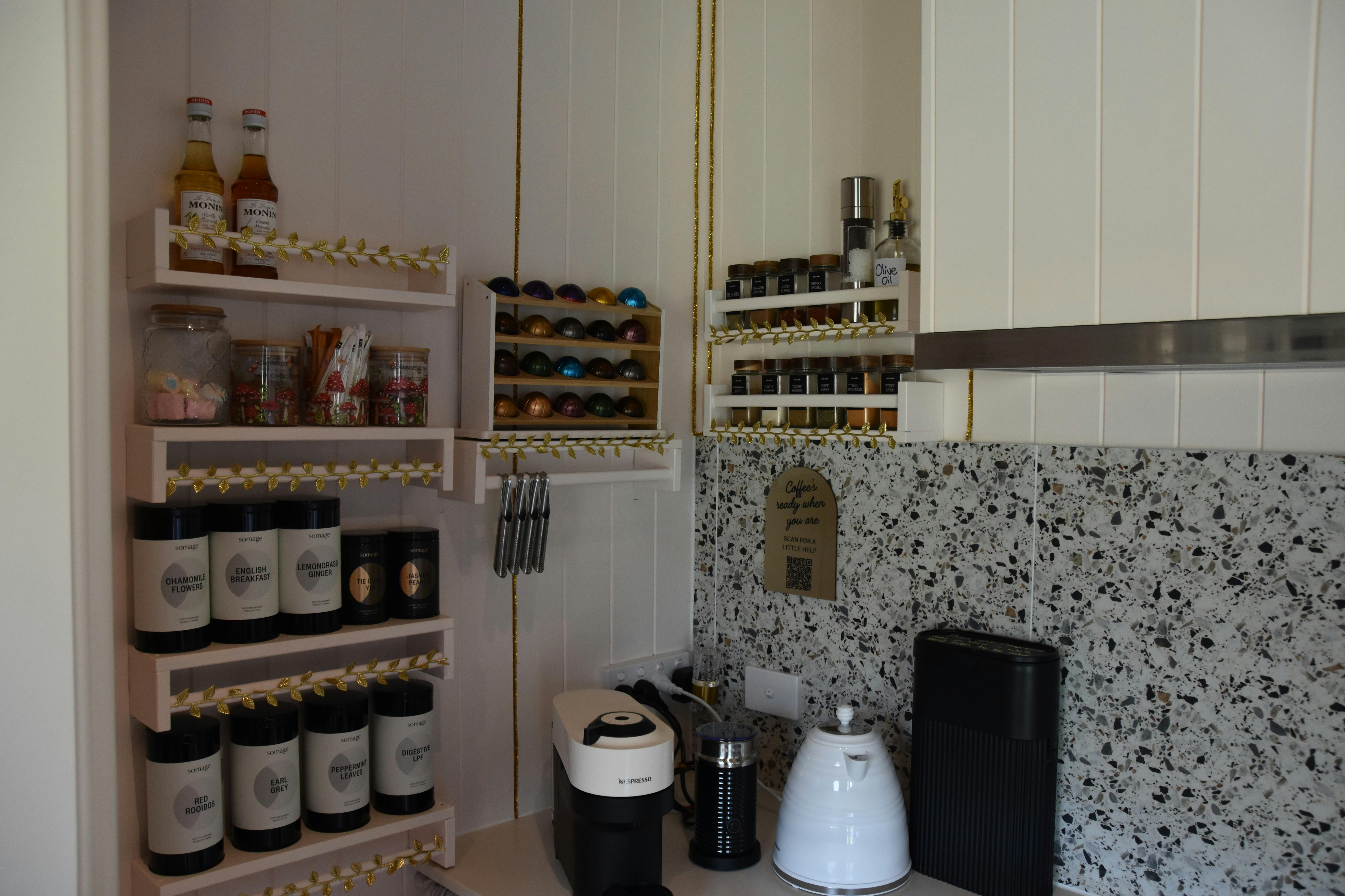 Shelving in Anwen kitchenette displaying teas, coffee machine and condiments