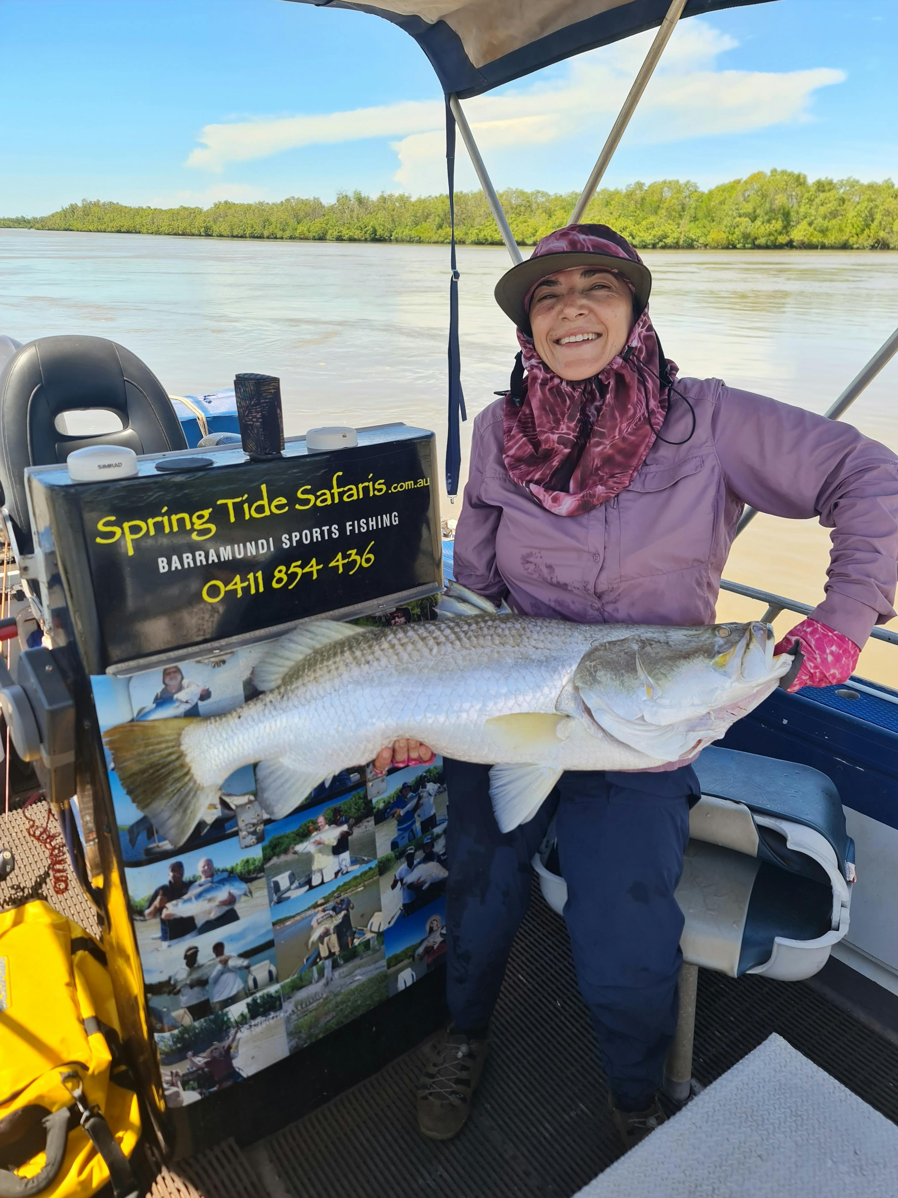 Carmen standing in a boat holding a 98cm barramundi.