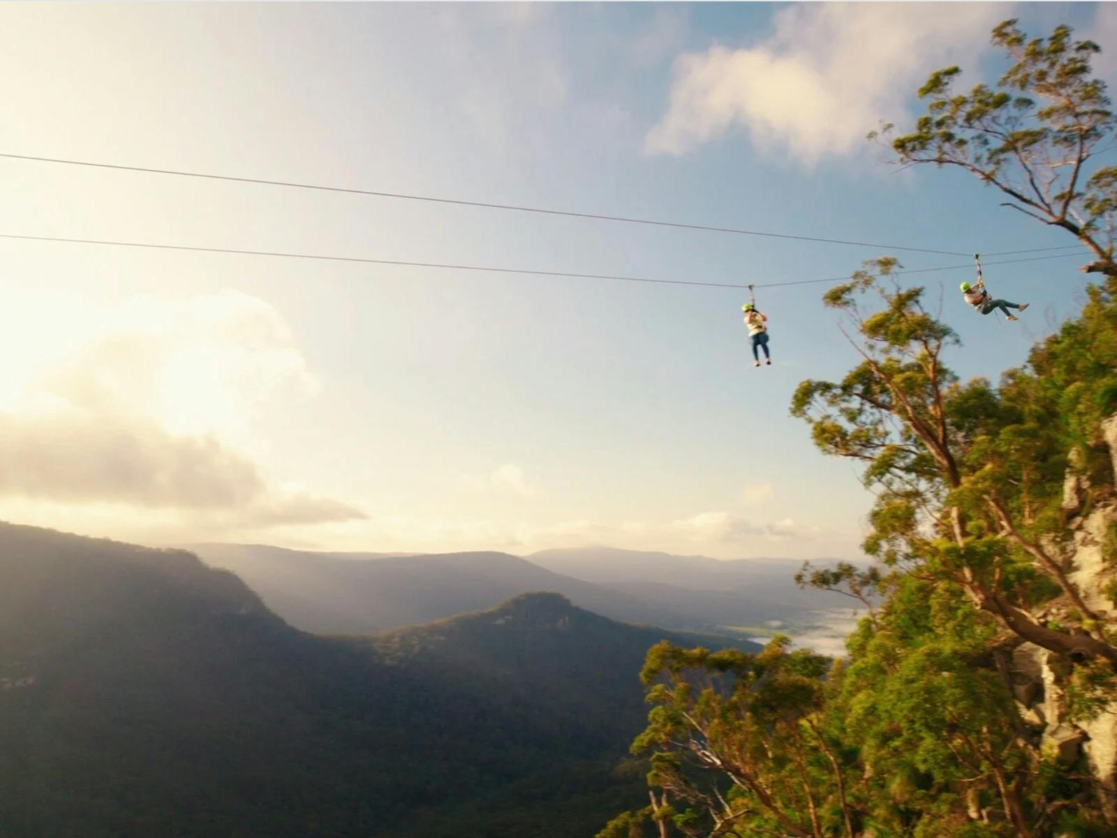 Adventurers soaring mid air on total exposure zipline. Adventurers soaring mid air on total exposure zipline.