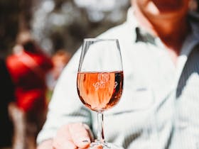 A man holds a wine glass with the Grazing logo