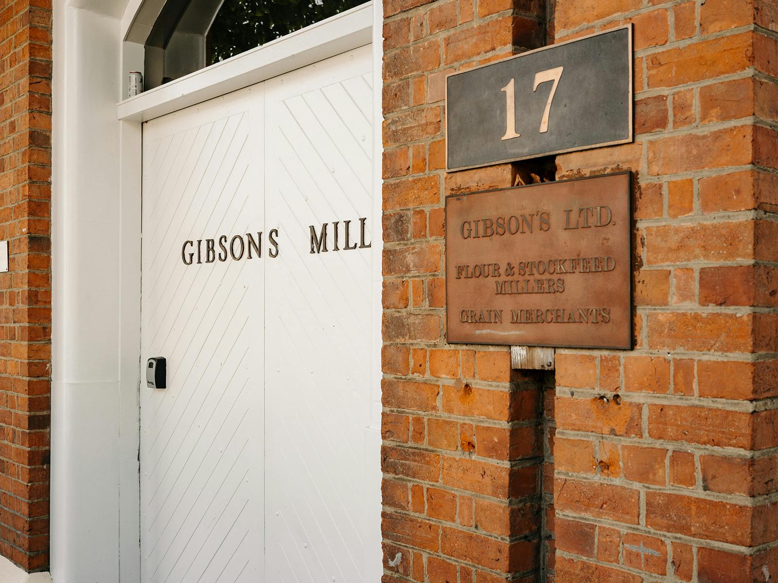 Brick exterior detail showing "Gibson's Mill" sign and door numbered 17.