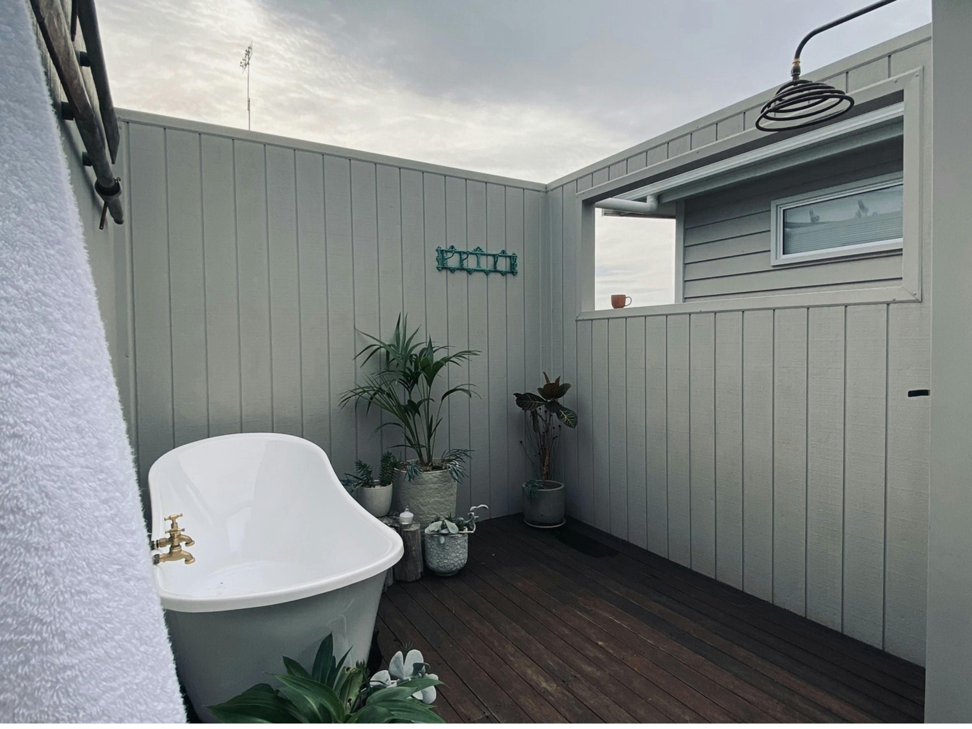Outdoor Bath & Shower - Bath sitting on deck surrounded by plants. Shower with cup of tea,