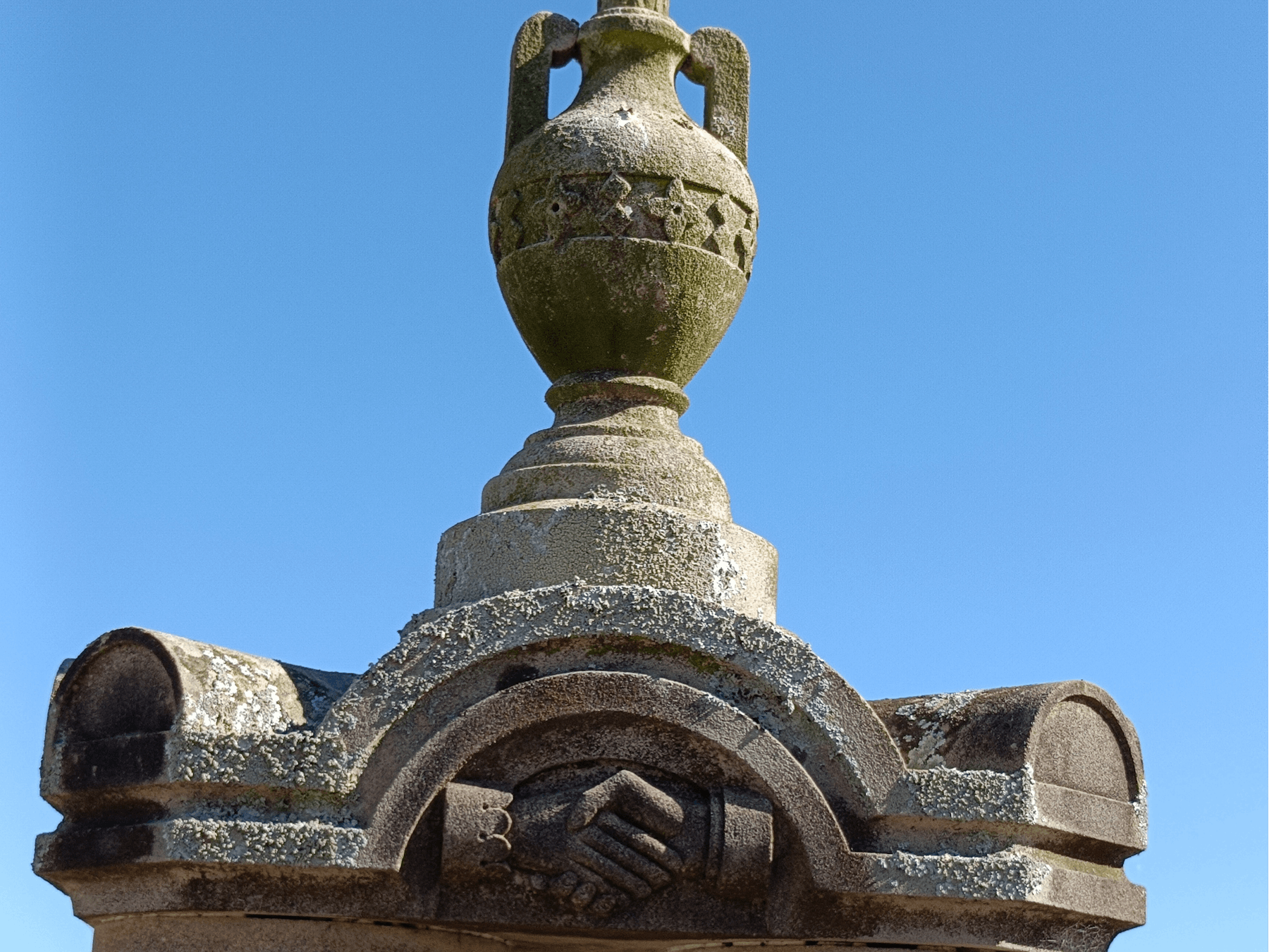 A cemetery monument with two hands clasped together
