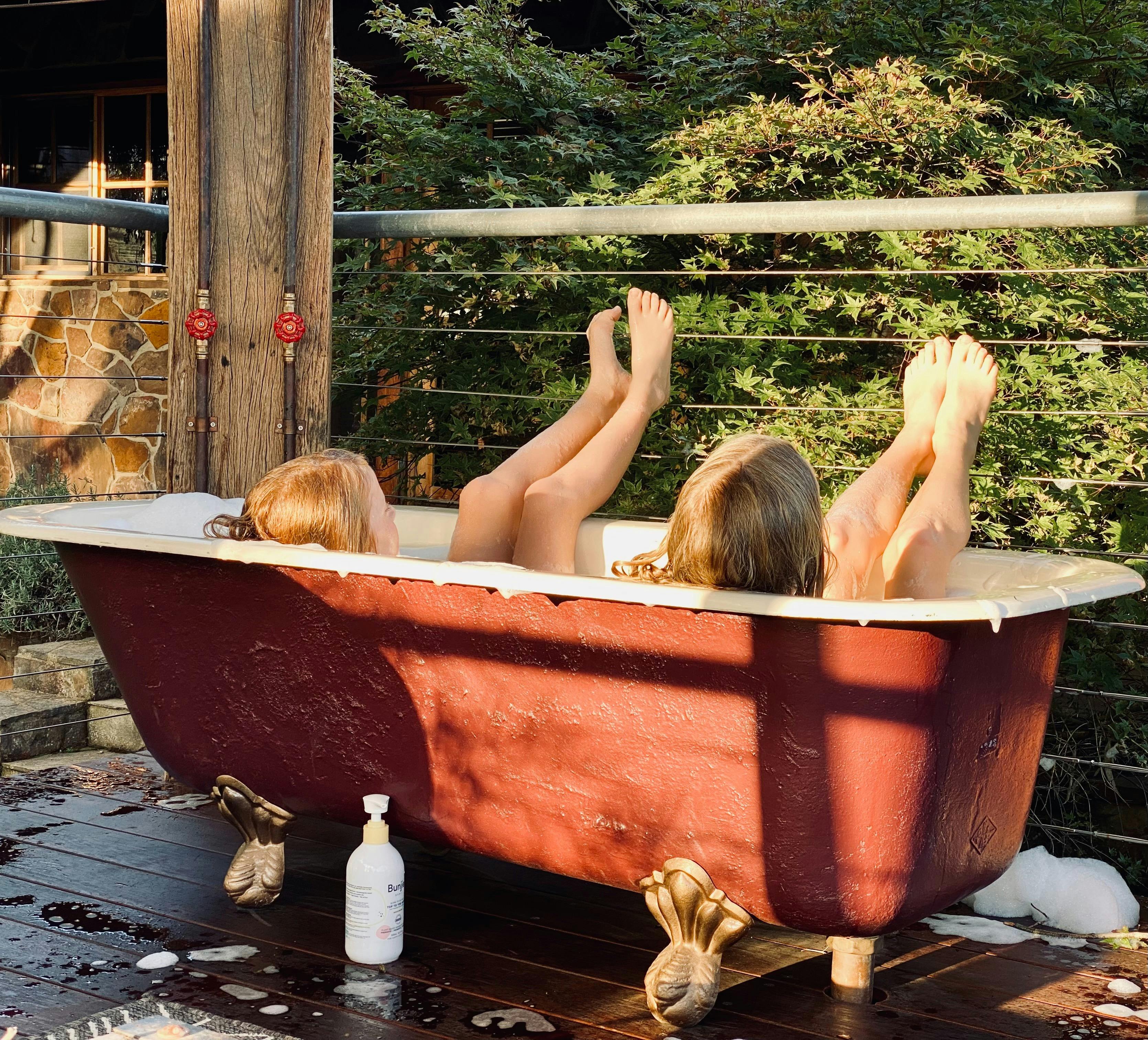 Very happy girls enjoying the outdoor cast iron bathtub at Stone Creek Cottage