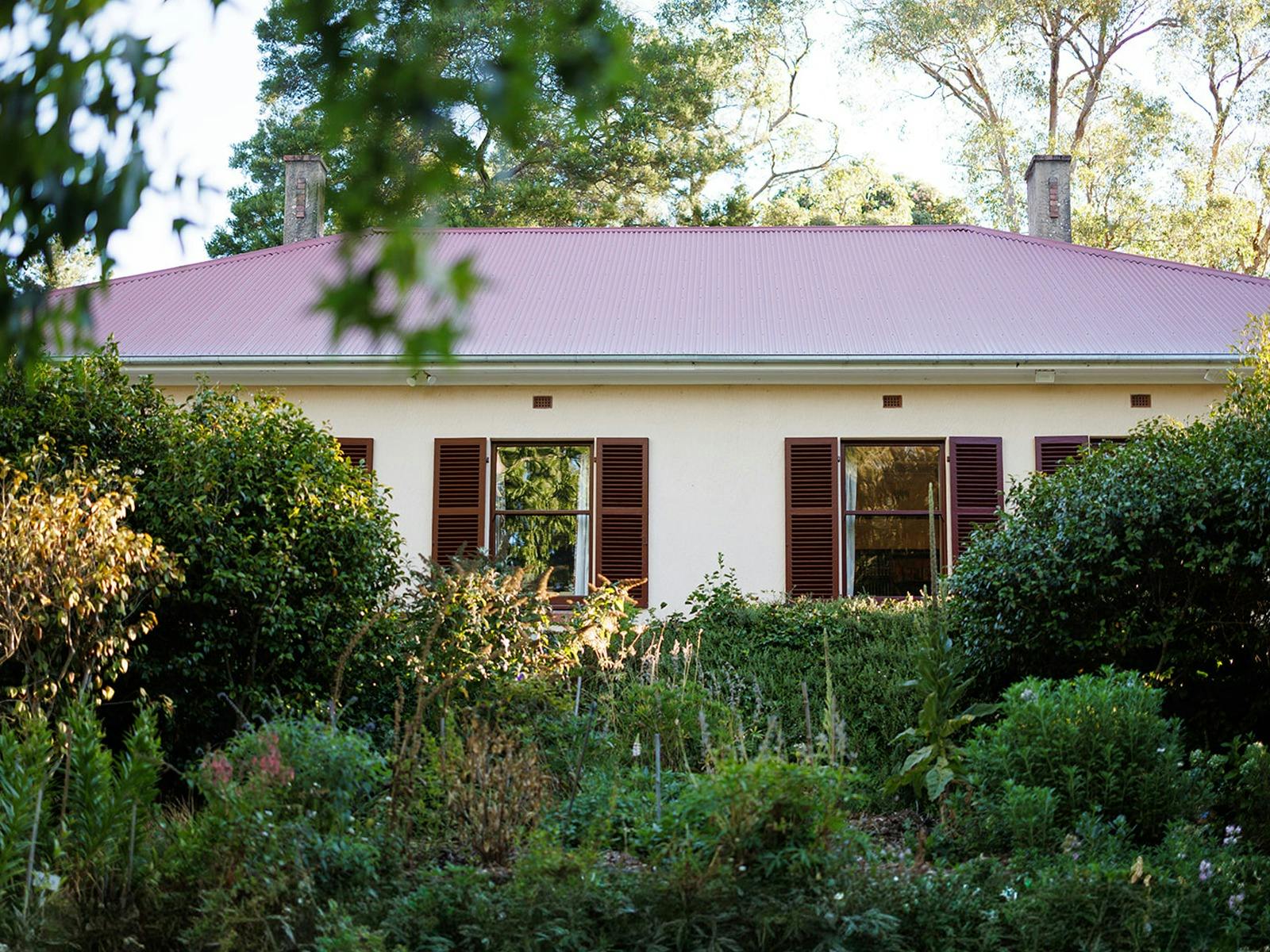 A historic house with a red roof in ornate gardens.