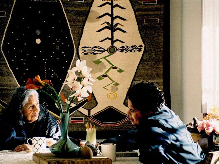 A film still featuring two artists sitting at a table.