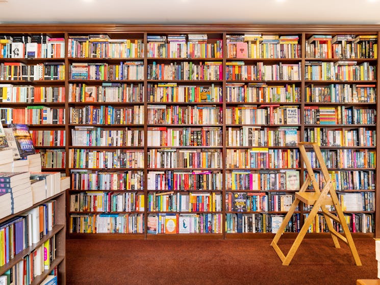 An inviting wall of fiction books from floor to ceiling.