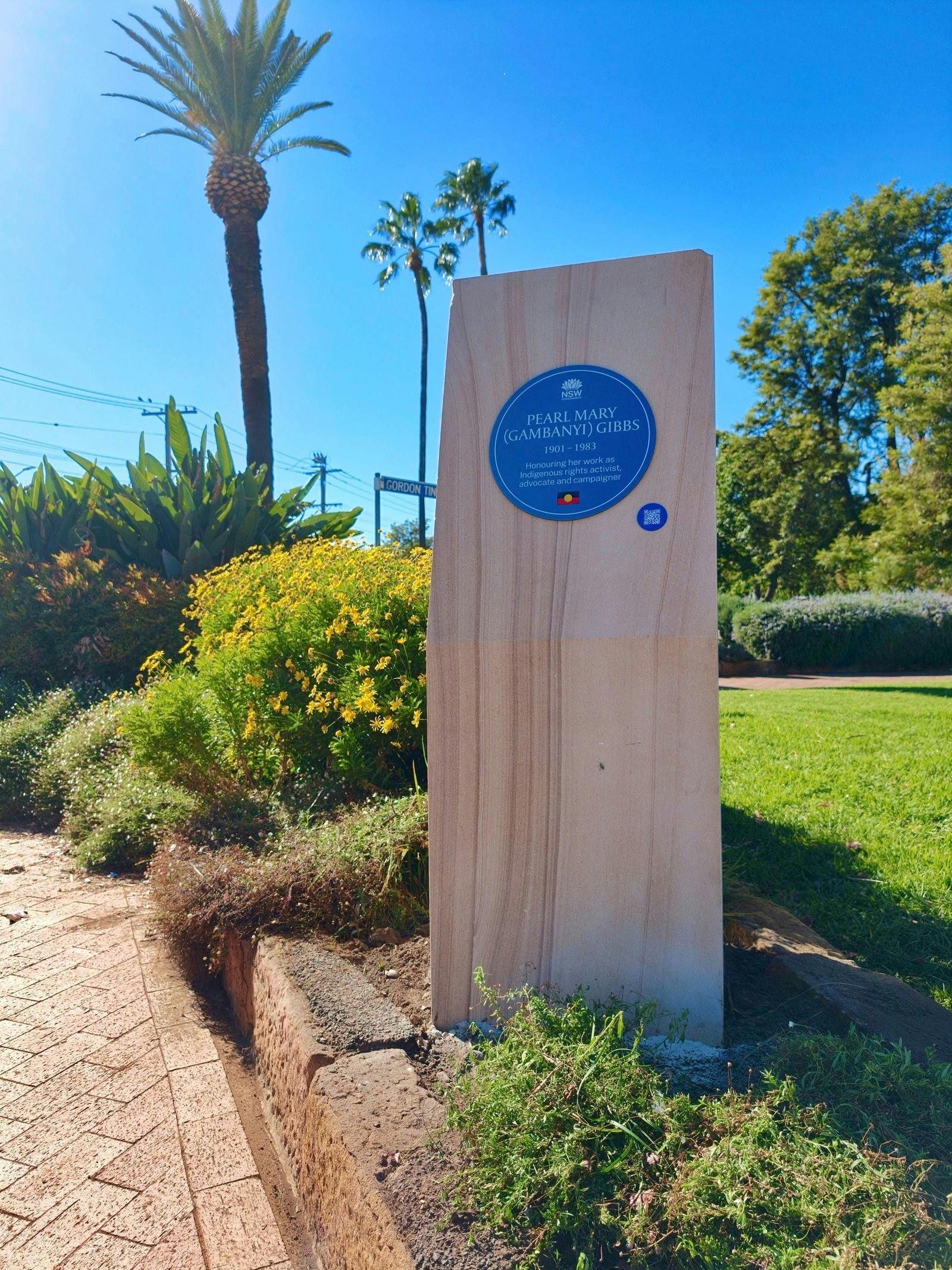 Blue plaque on sandstone plinth in garden setting