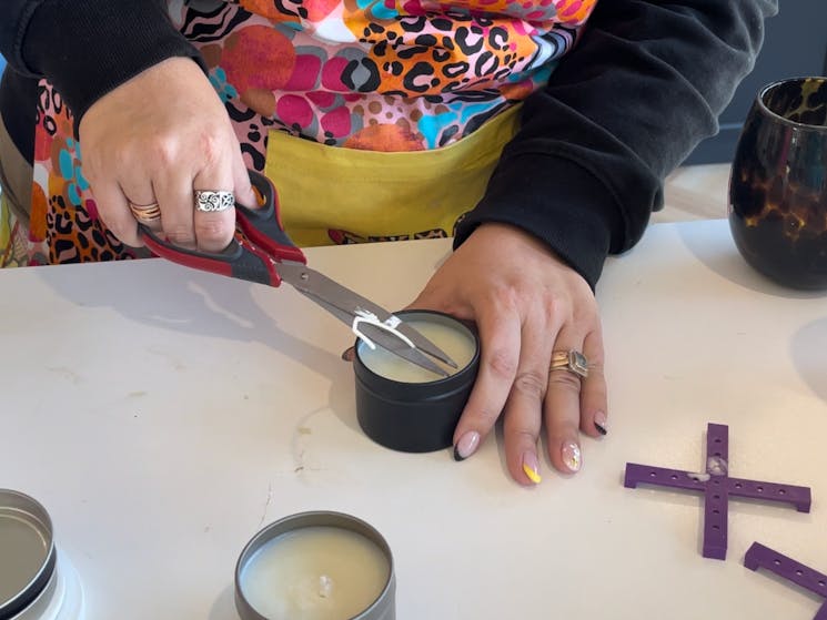 A workshop participant cutting the wick of a tin candle