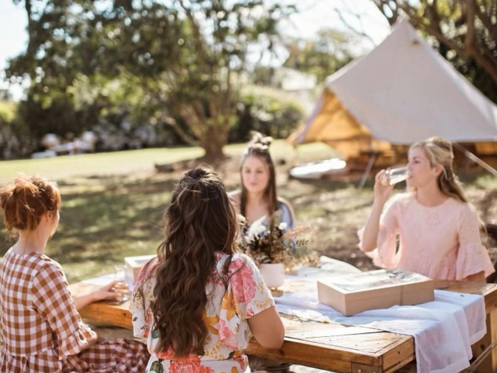 Group of ladies sitting around our bespoke sunshine styled picnic at The Soul Nook