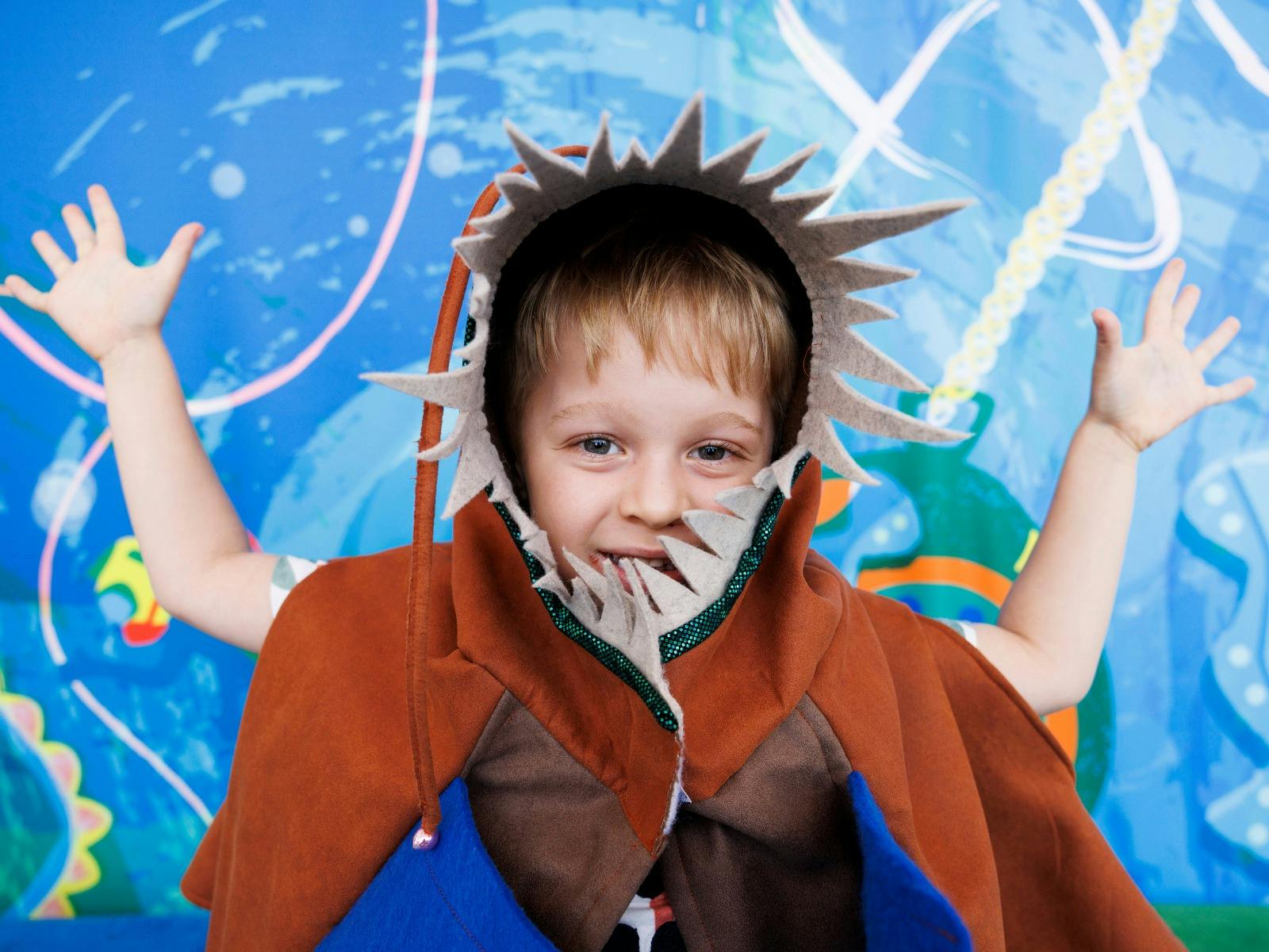 A young boy dressed in a shark costume smiles at the camera
