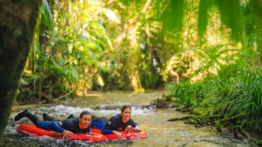 2 people laying on red river sleds, floating through the river 2 people laying on red river sleds, floating through the river