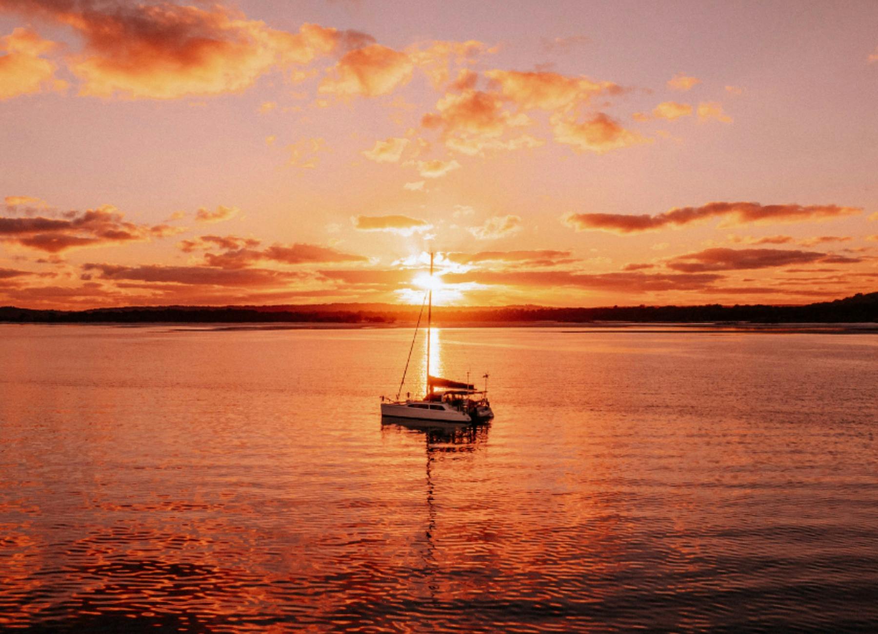 Catamaran on the water with ocean sunset over K'gari - Fraser Island in the background