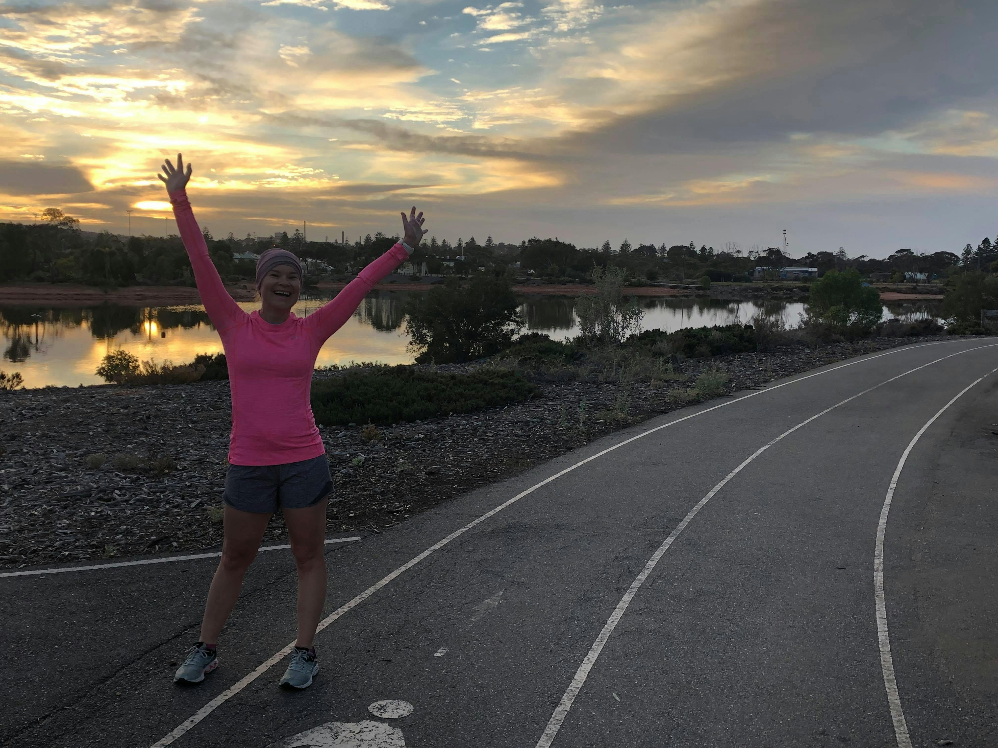 Person standing with hands in the air welcoming the morning sun