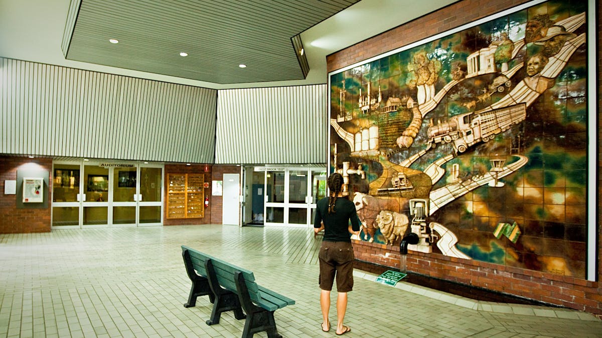 A person with braids and a black shirt looking at the Three-Dimensional Mural