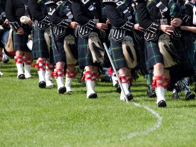 Image of pipers in Scottish dress , marching and playing bagpipes