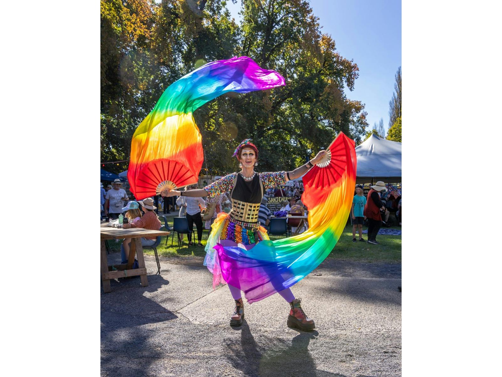 A drag king dances with rainbow fans and silks