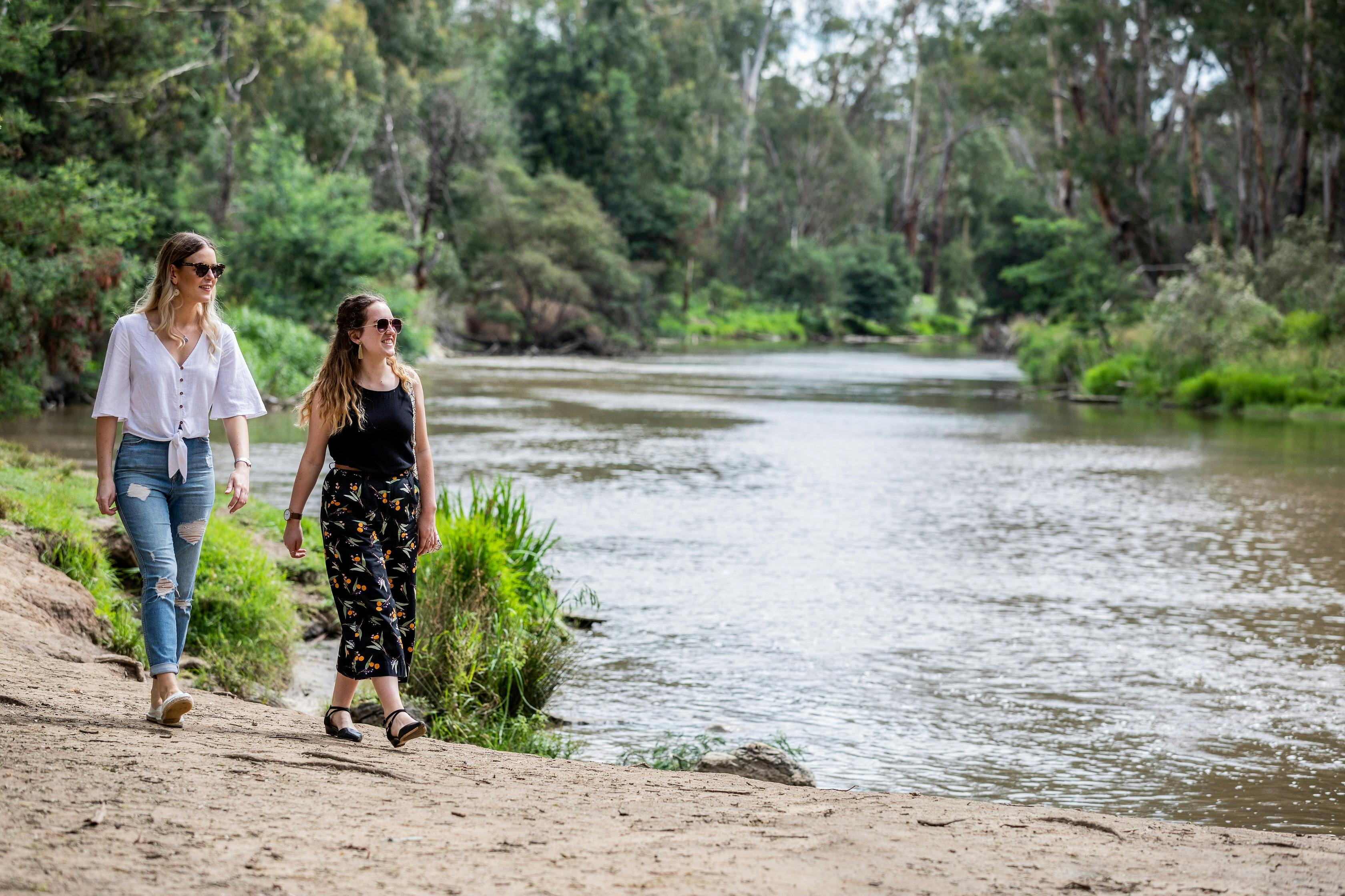 Two wonen walking alongside river