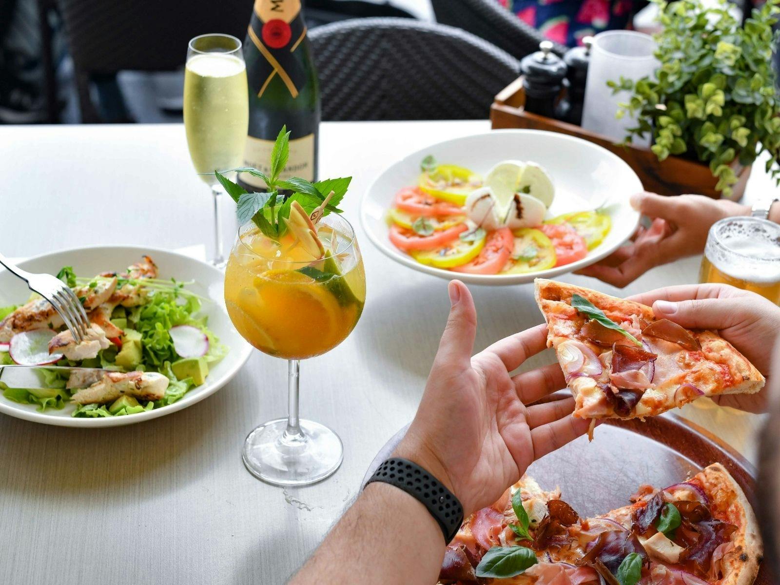Eastbank Cafe outdoor table set up with pizza and salads and a sangria cocktail and champagne