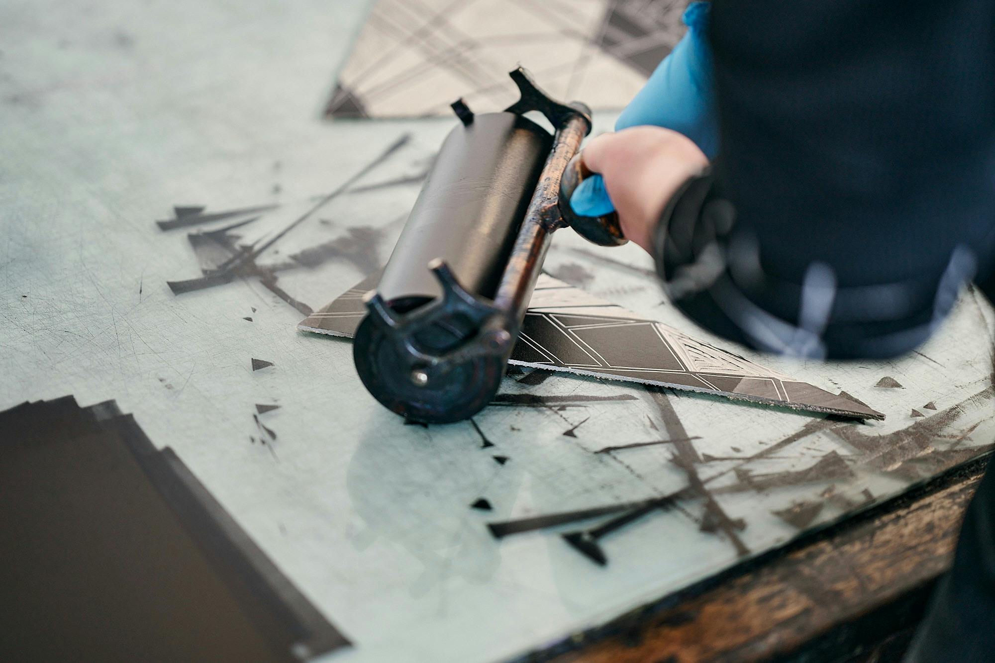 A roller inks up a relief block before printing