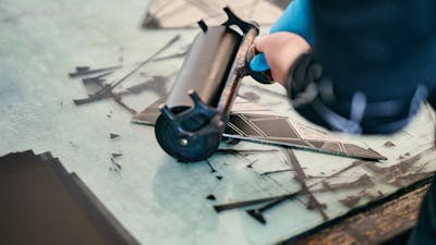 A roller inks up a relief block before printing