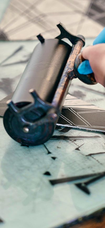 A roller inks up a relief block before printing