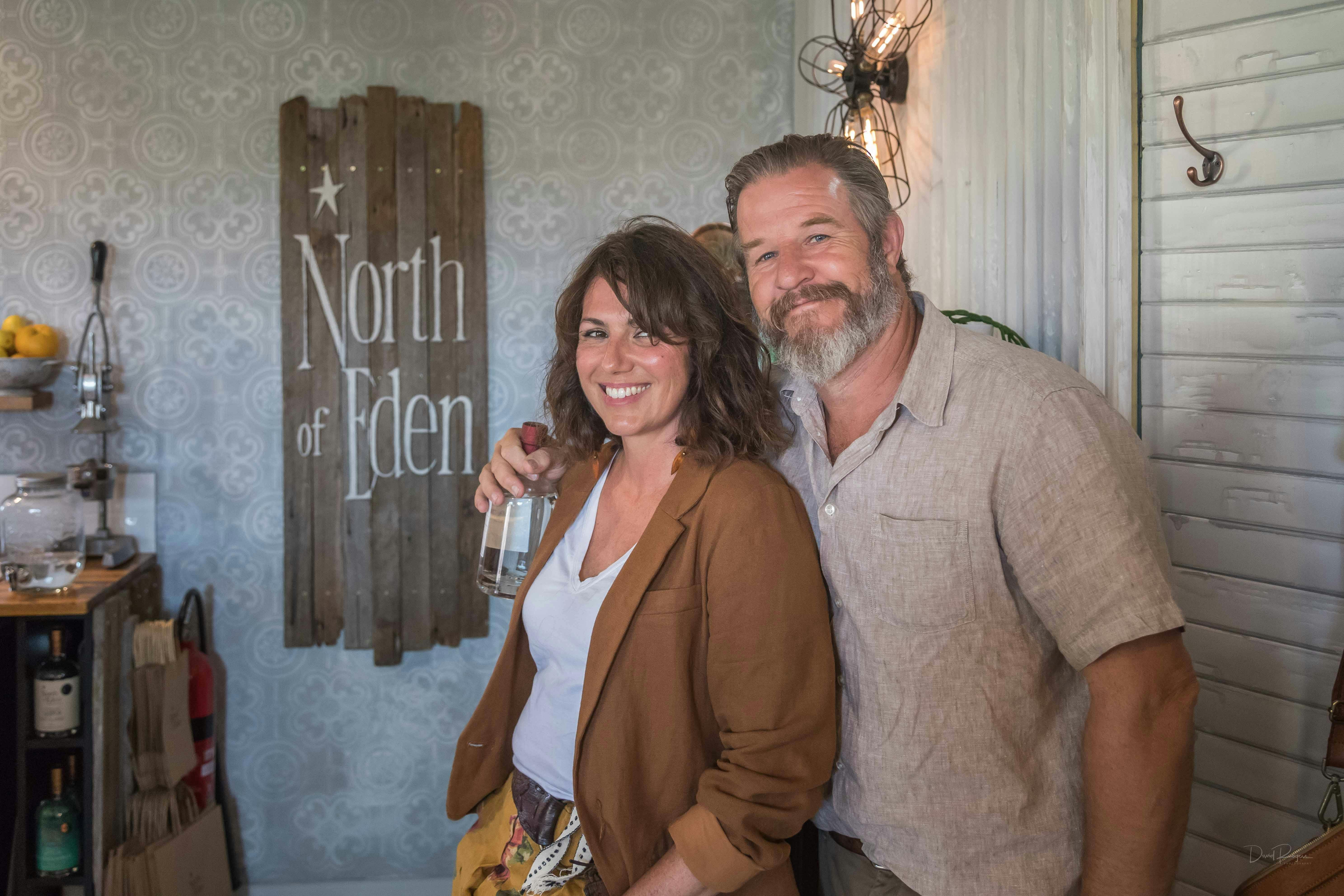 Man and woman standing in front of a sign with a bottle of gin
