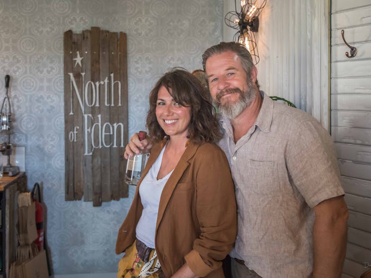 Man and woman standing in front of a sign with a bottle of gin