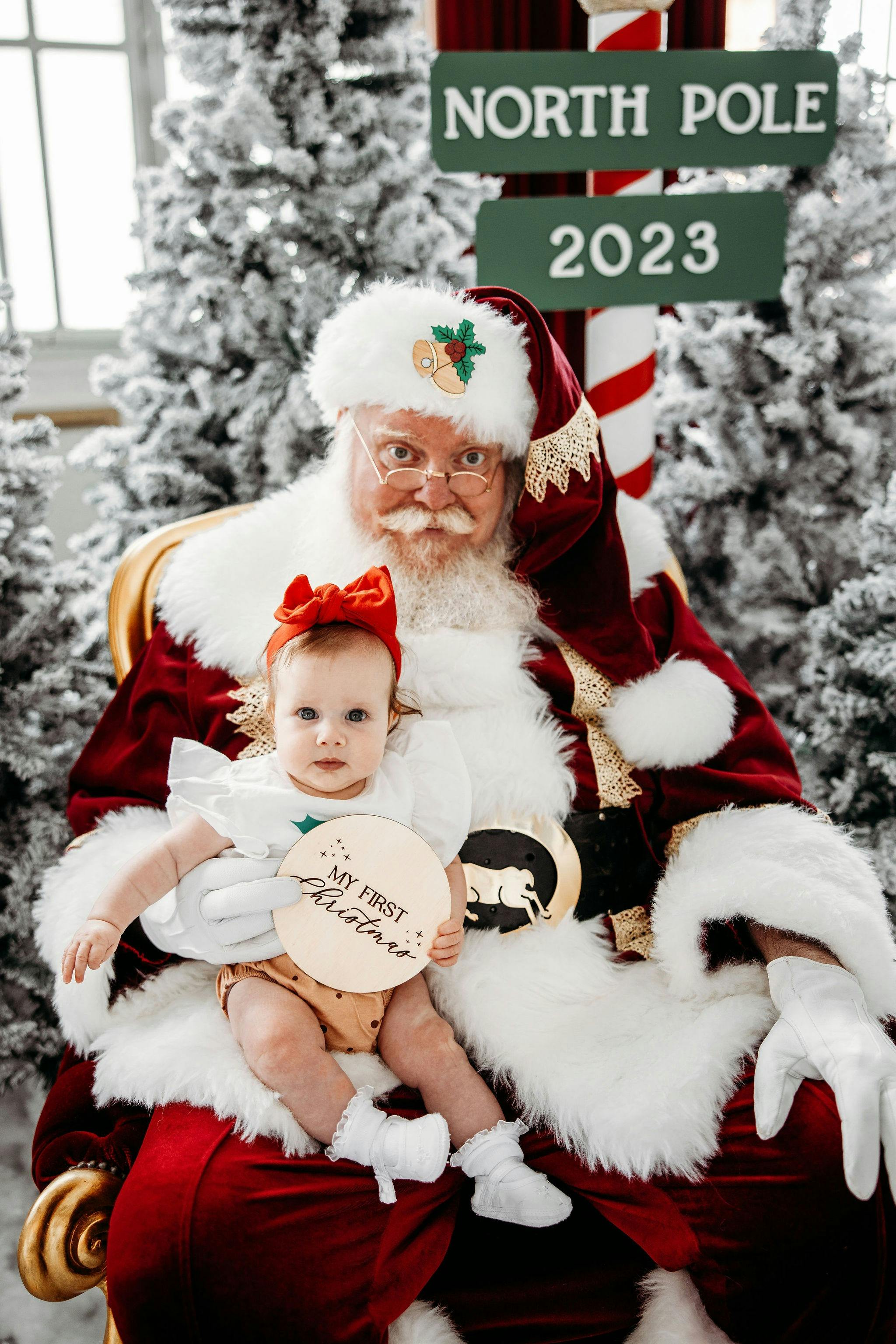 Santa with a child sitting on his lap. A family sitting with santa.