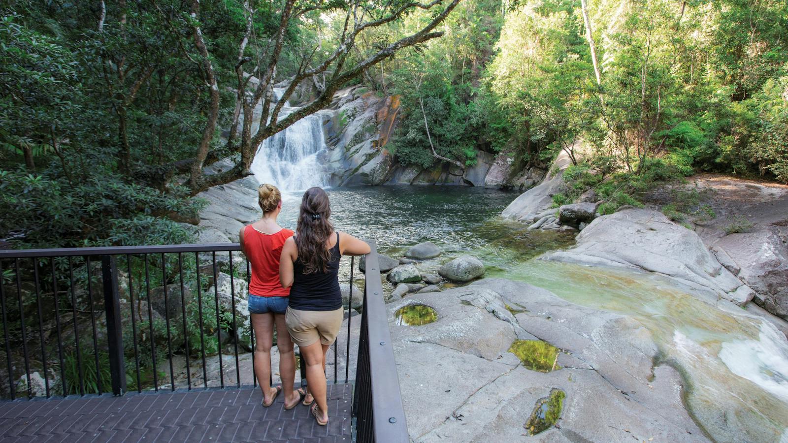 Two people standing at lookout over top pool and falls.