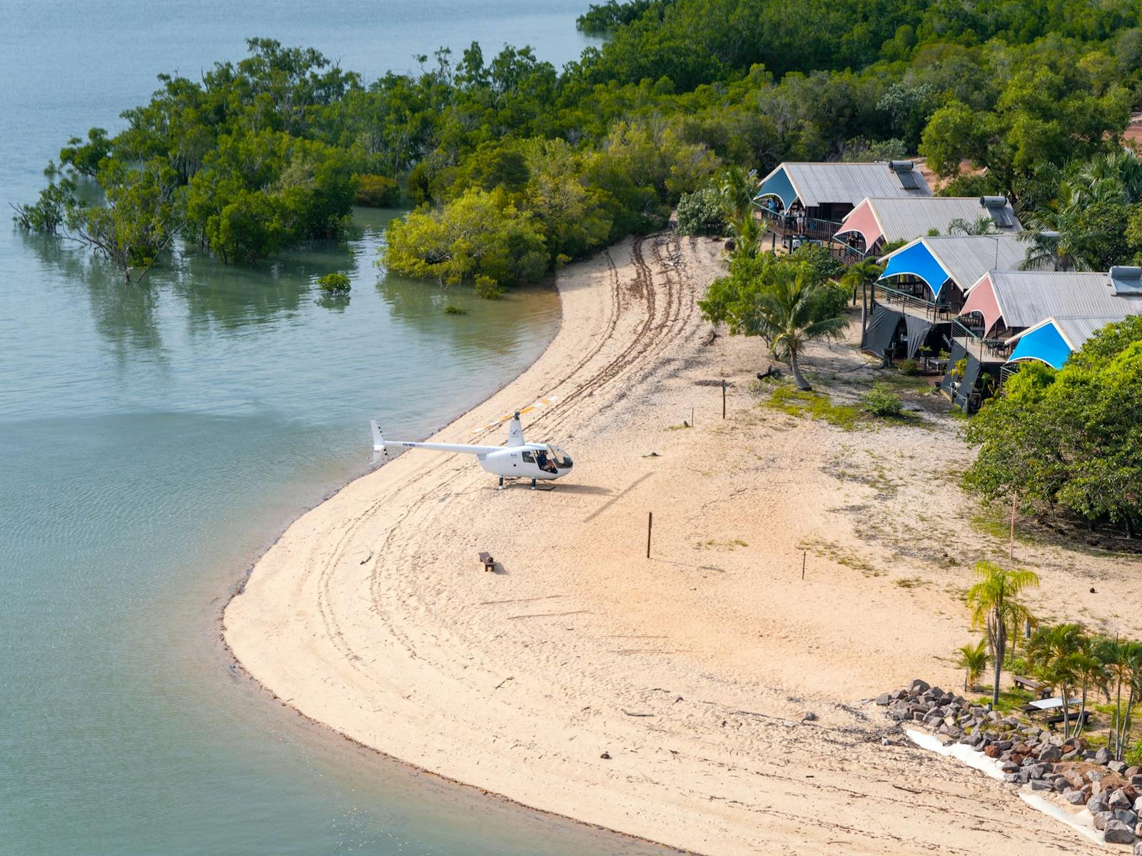 Aerial photo of a white helicopter parked on the beach in front of Crab Claw Island Resort