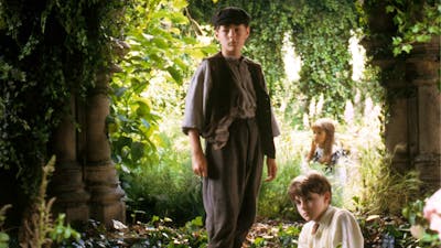 Three young children sitting within a garden