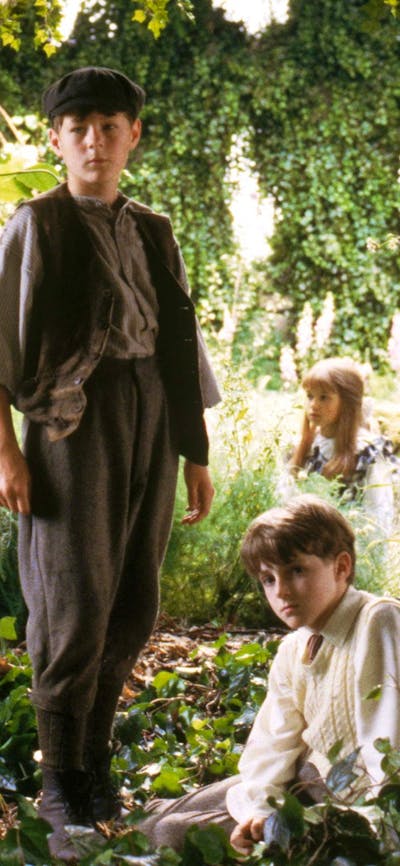 Three young children sitting within a garden