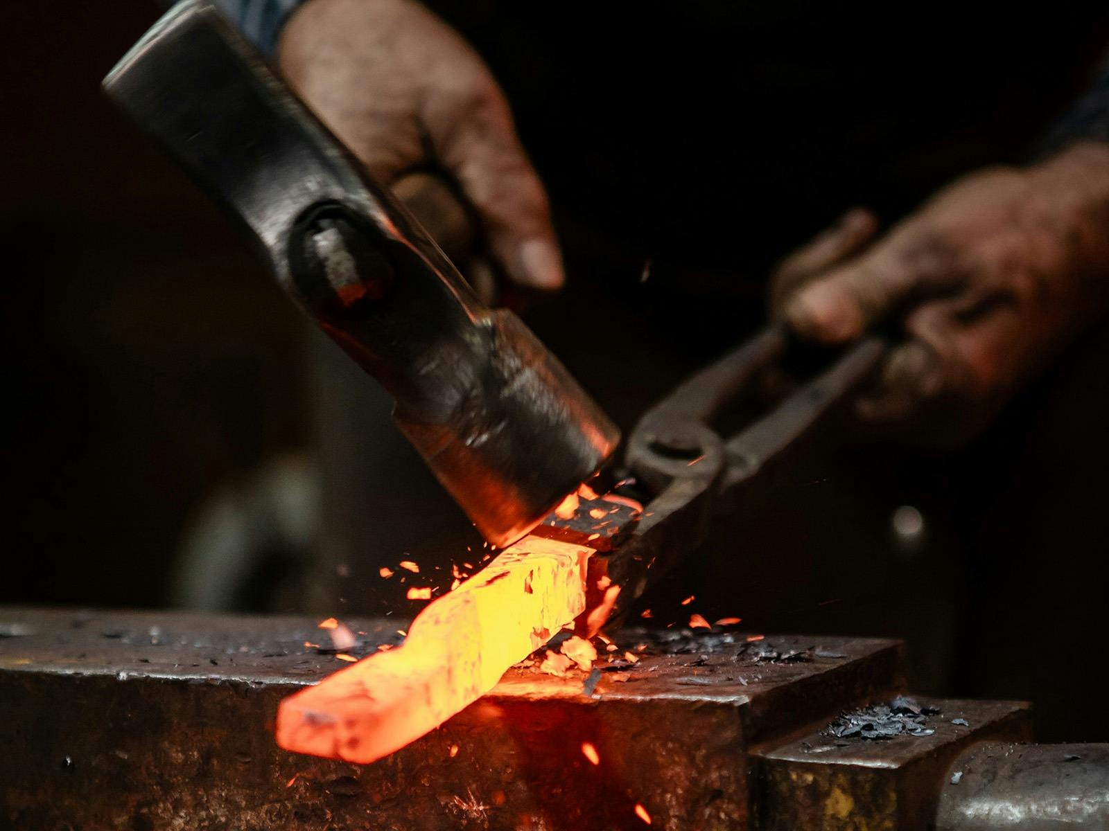 Hammer striking heated metal on anvil. Hammer striking heated metal on anvil.