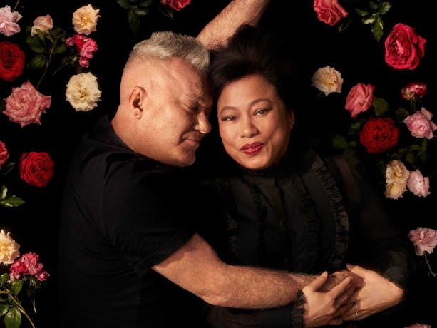 Two adults embracing on a bed of roses.