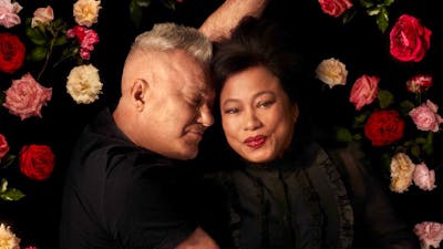 Two adults embracing on a bed of roses.