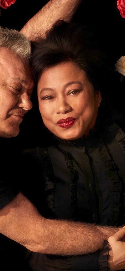 Two adults embracing on a bed of roses.