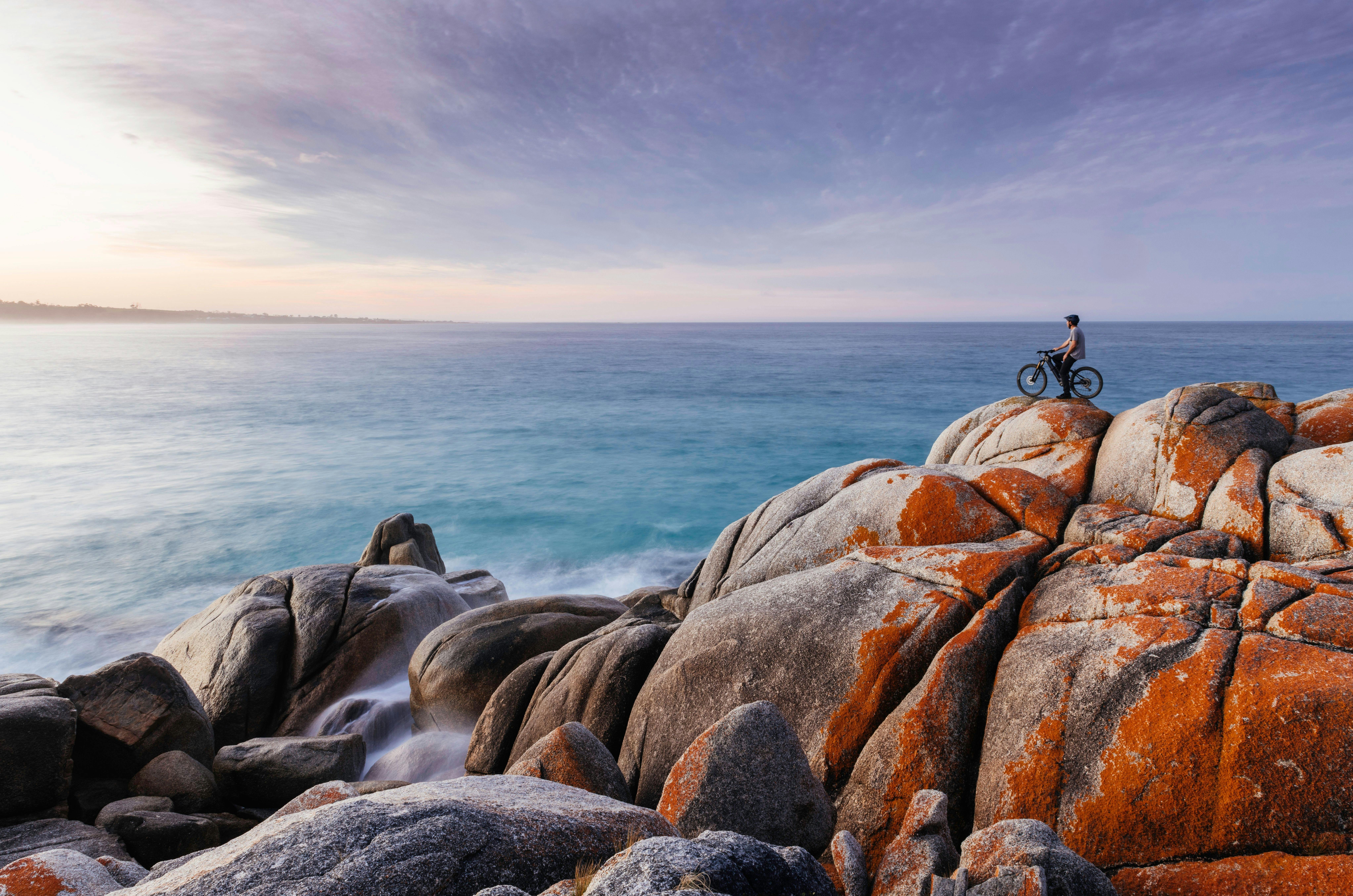 Cyclist on Bay of Fires granite rocks with ocean views in Tasmania