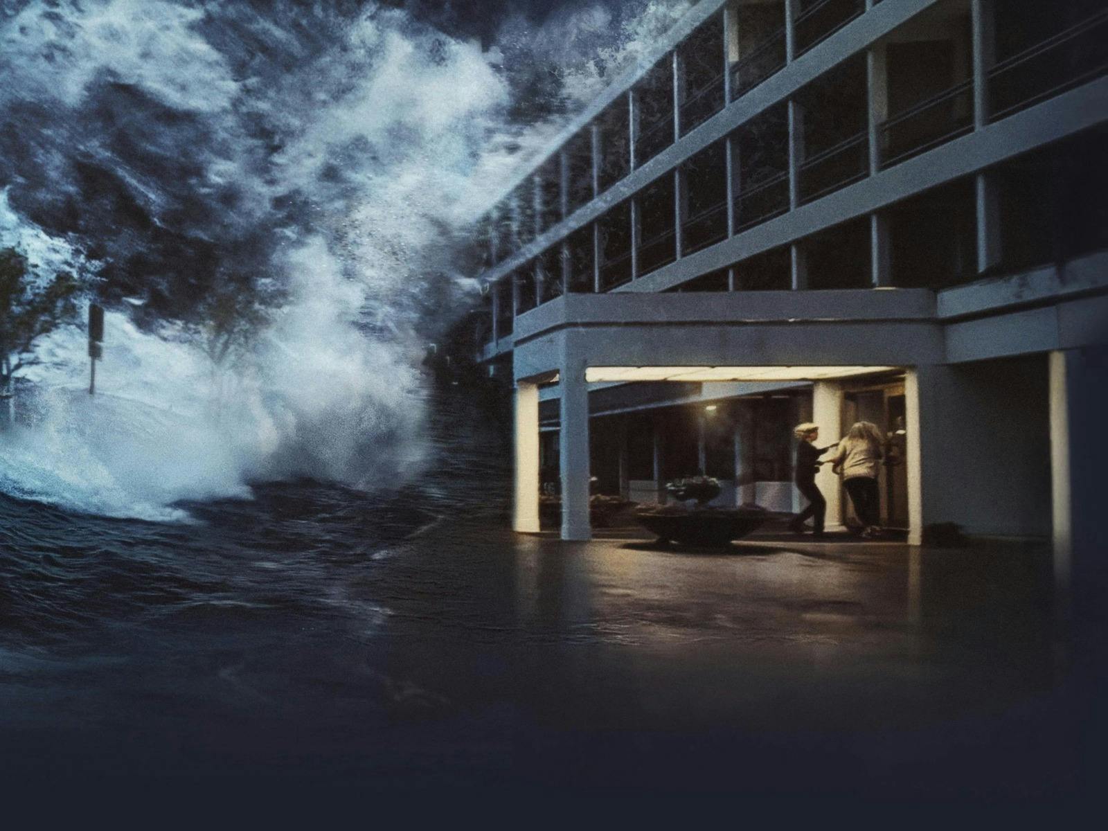 Still of two people running into a building while a wave larger than the image is coming towards the